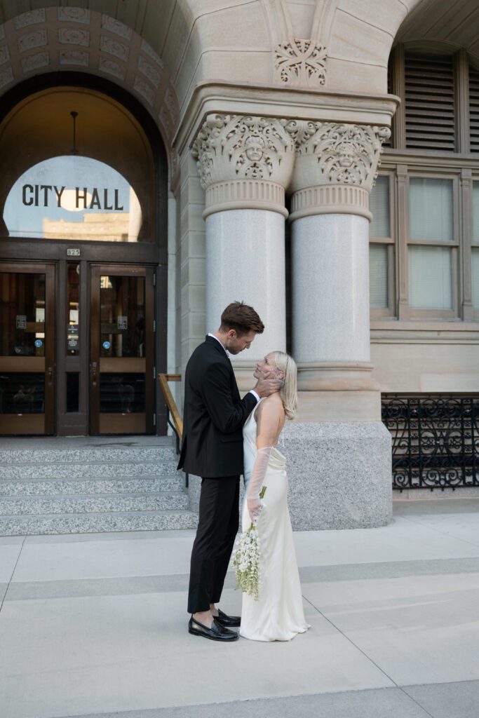 Couple poses at Milwaukee City Hall during their intimate elopement ceremony.