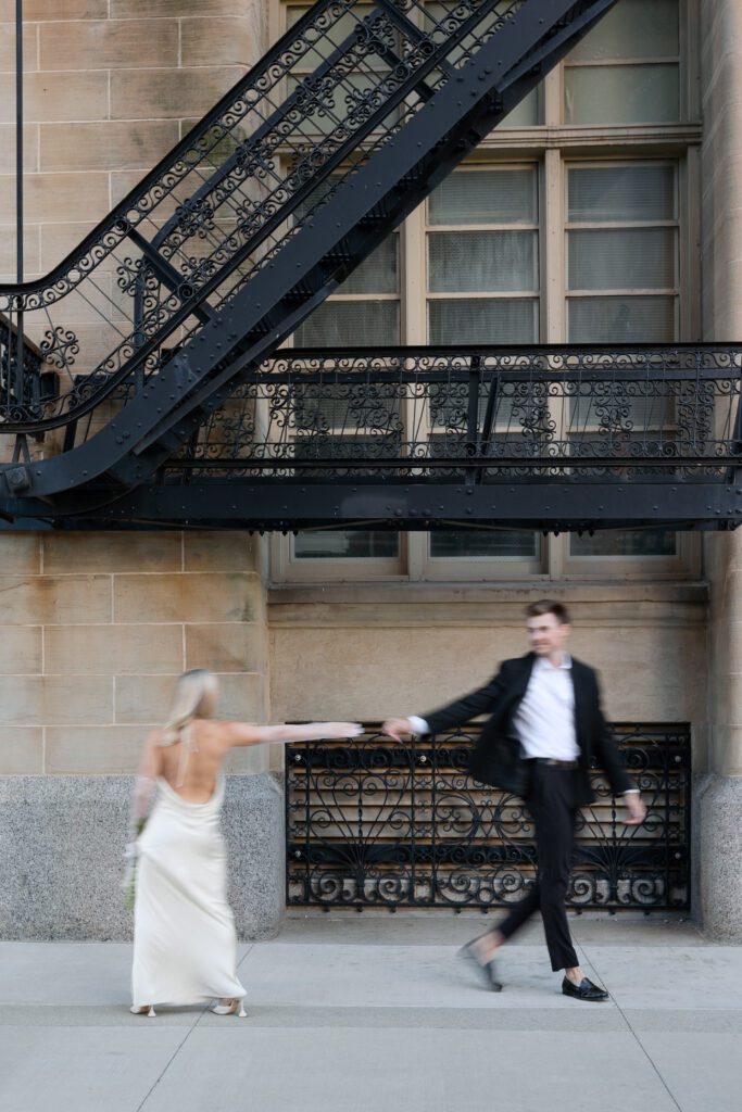 Bride and groom framed by Milwaukee City Hall's historic arched windows.