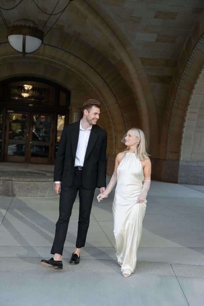 Newlyweds walk away from Milwaukee City Hall, glowing with post-elopement joy.