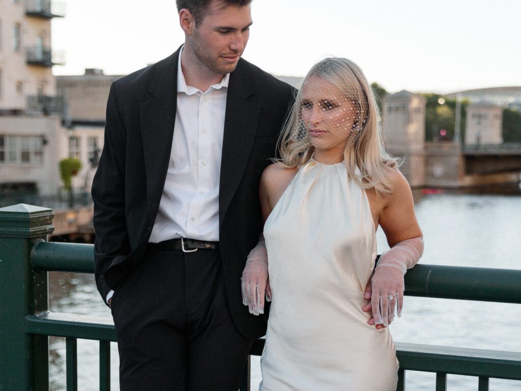 Bride and Groom leaning on railing at the Milwaukee Riverwalk for portraits.