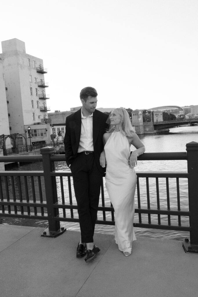 Bride and groom leaning on railing by the Milwaukee Riverwalk during their elopement.