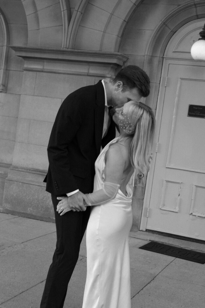 Milwaukee City Hall elopement featuring a romantic kiss beneath its grand facade.