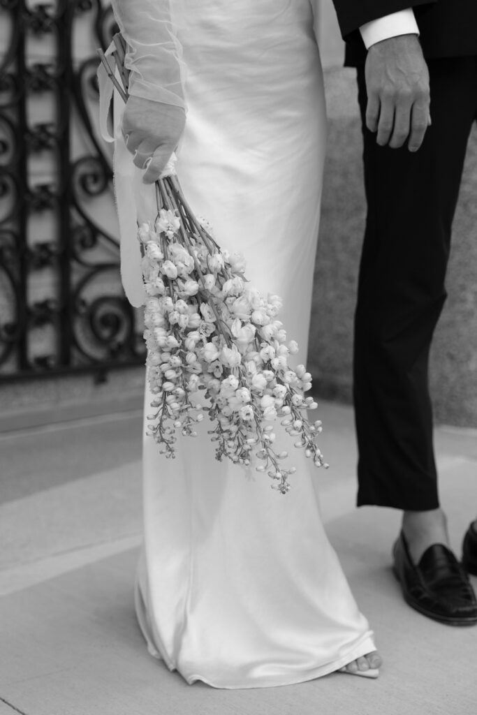 Black and white photo of bride's floral bouquet at her side.