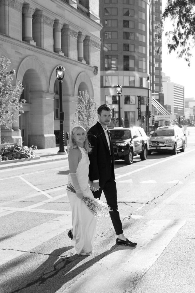 Bride and groom walking across street at their Milwaukee City Hall Elopement.