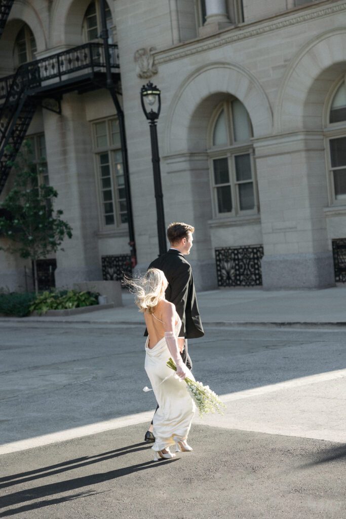 Bride and groom walking across street in Milwaukee, Wisconsin.