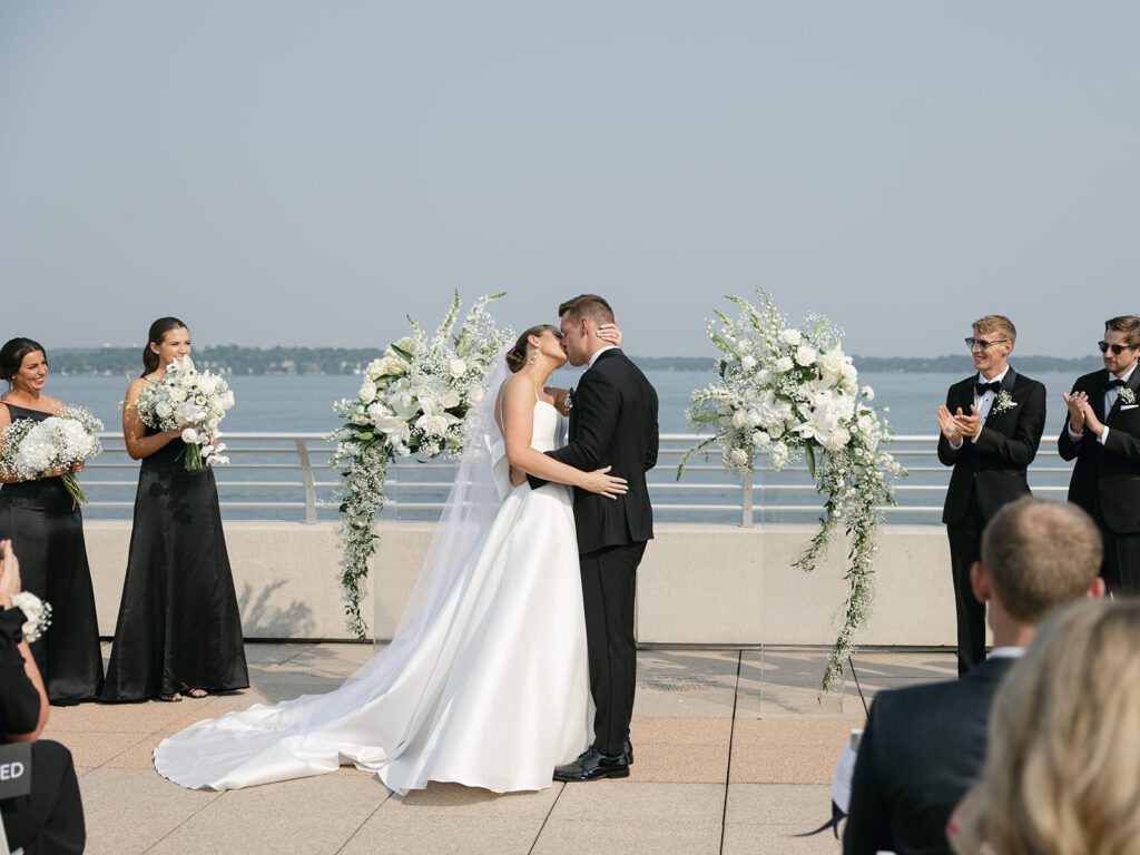 first kiss during ceremony at the Monona Terrace with Lake Monona as the backdrop