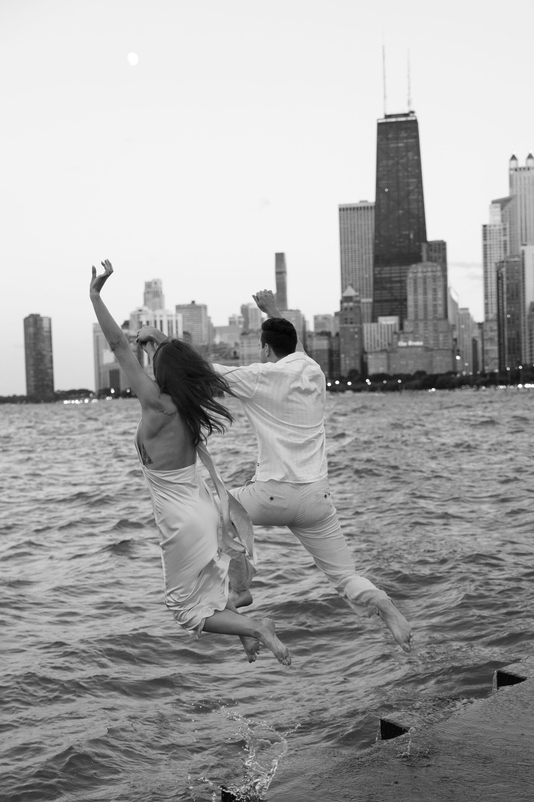 Engagement couple jumping into Lake Michigan at North Avenue Beach in Chicago.