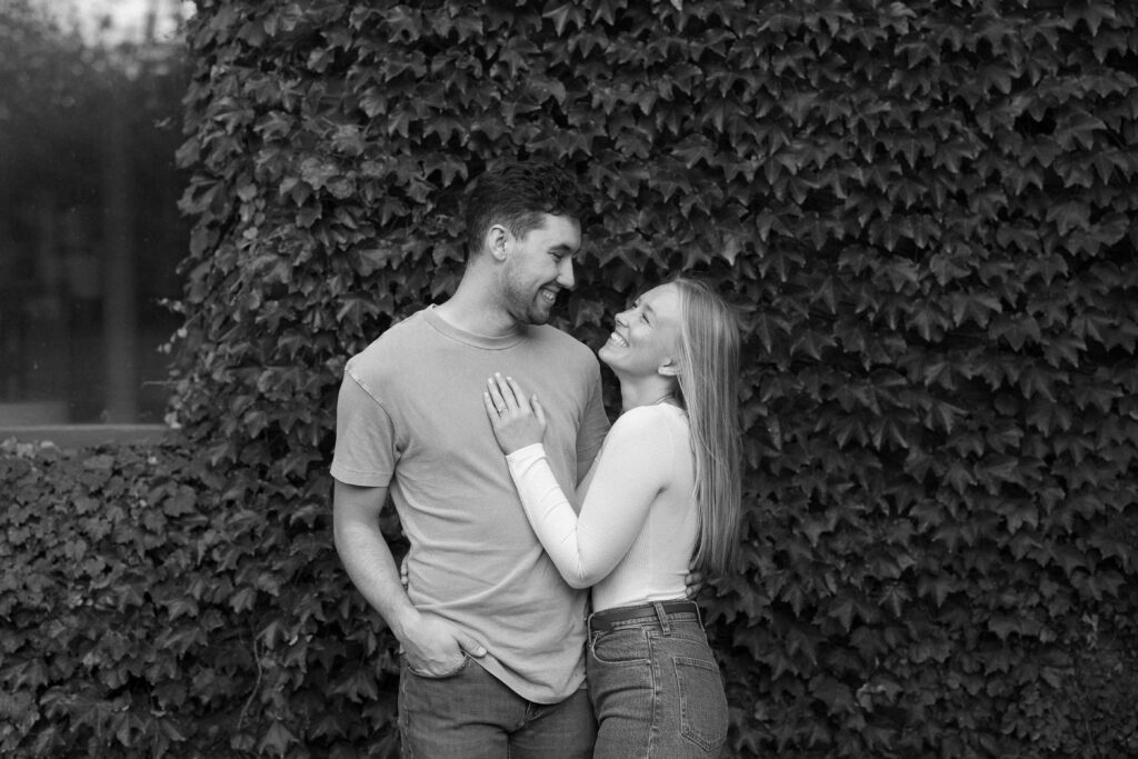 Couple embraces at a ivy wall during their engagement session in Madison, Wisconsin.