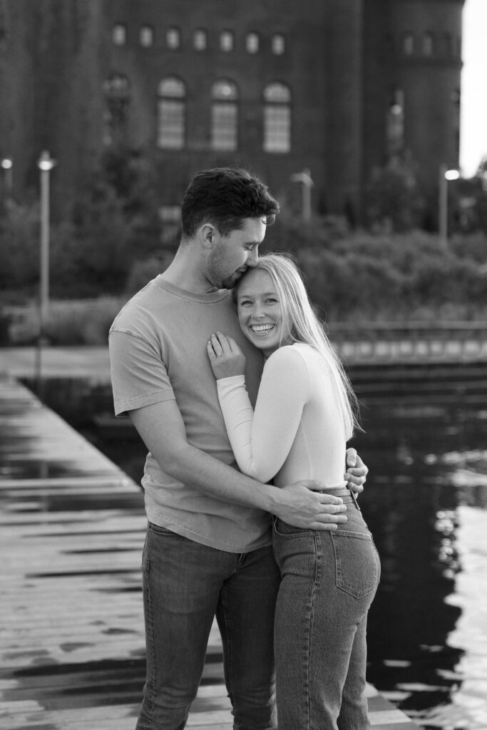 Black and white of a couple hugging at their engagement session on a pier on Lake Mendota in Madison.