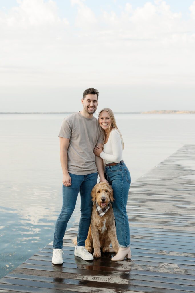 Couple on the Memorial Union pier with their dog smiling at the camera.