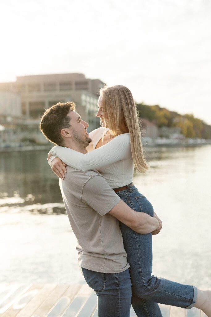 Couple embracing and spinning on the lake with the Memorial Union in the background.