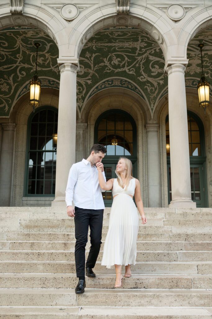 A Memorial Union engagement session couple kissing hands as they walk down the steps.