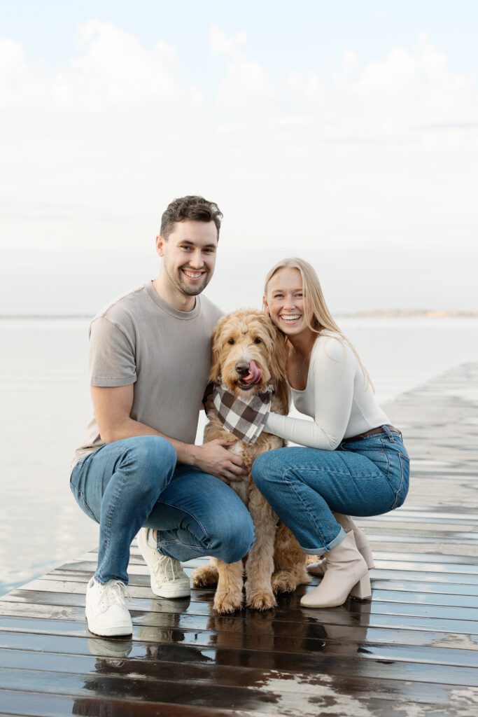 Couple smiling with their dog on a pier by the Memorial Union.