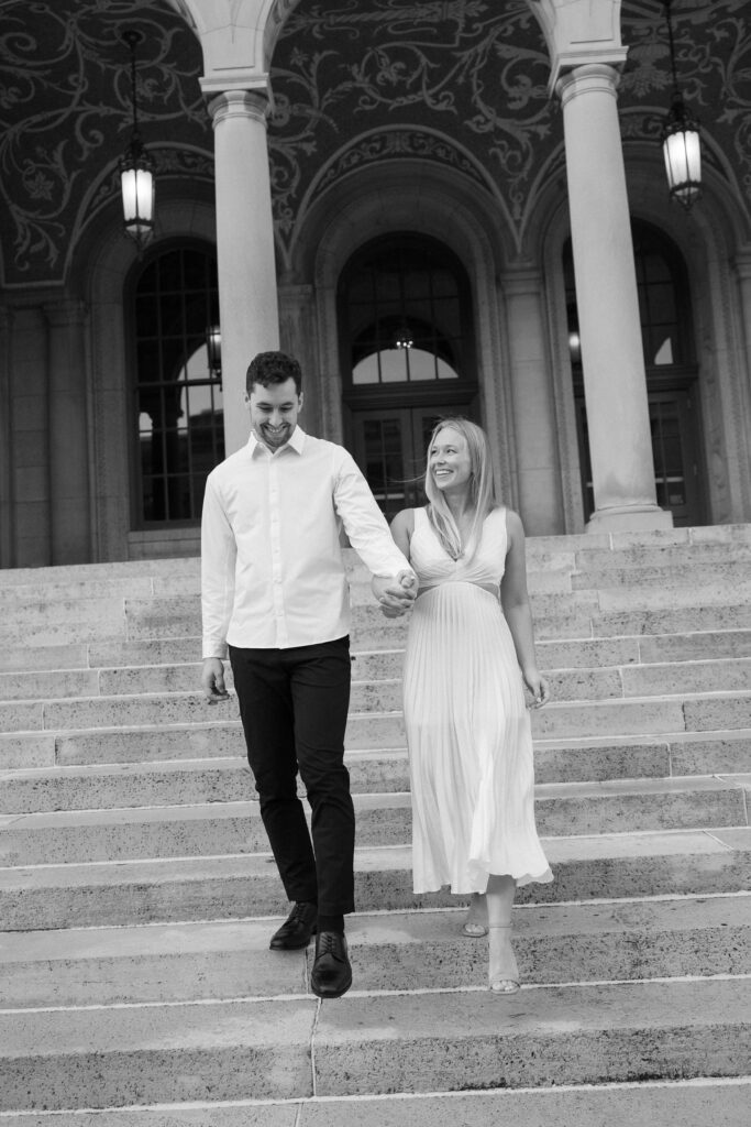 Black and white of a couple holding hands while walking down steps at the Memorial Union.