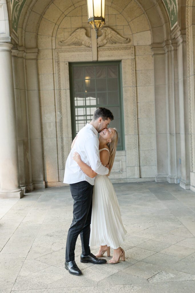 Engaged couple smiling forehead to forehead at the Memorial Union