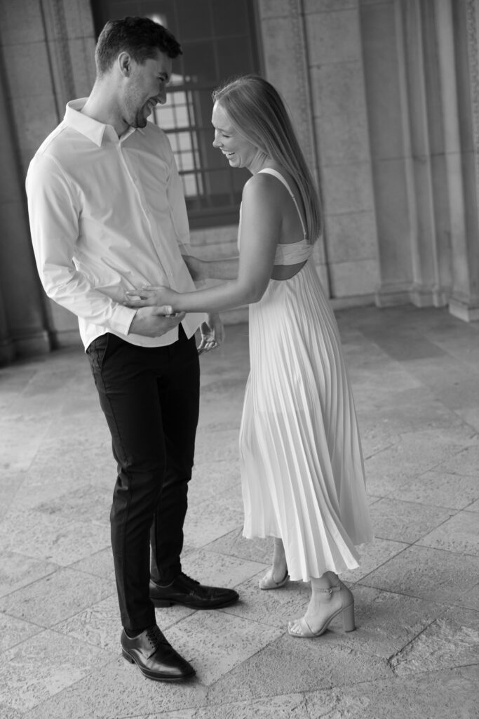 Couple gently holding hands and laughing at their Memorial Union engagement session.