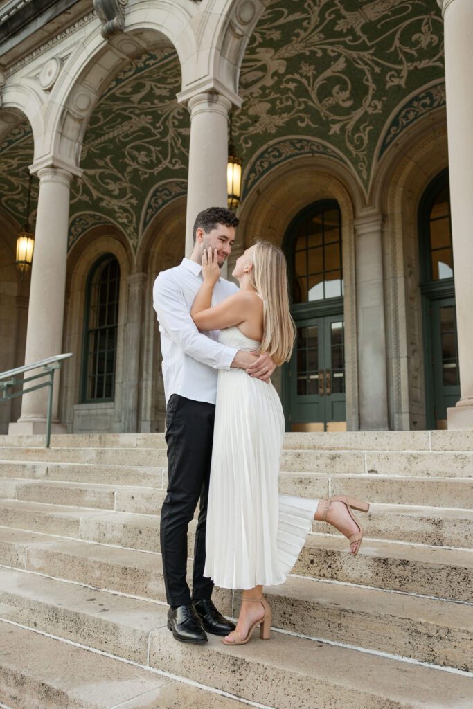 Engaged couple embracing near the Memorial Union pillars.