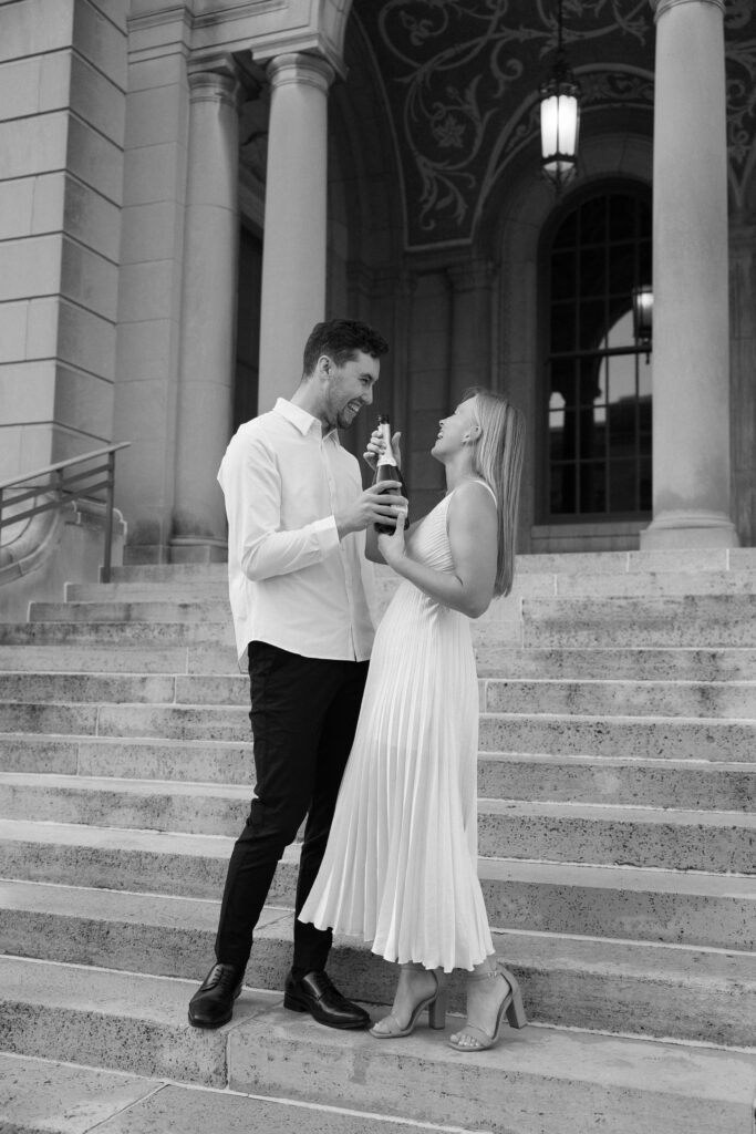 Couple laughing with champagne at their engagement session.