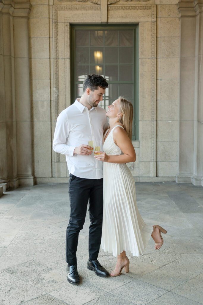 Couple embracing with champagne at their engagement session at the Memorial Union.