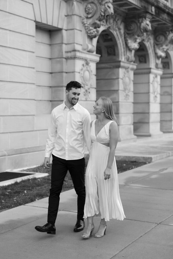 Engaged couple walking with Memorial Union views in the background.