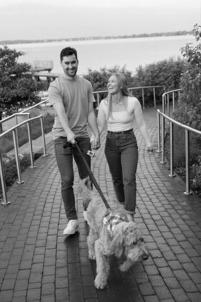 Couple laughing and walking their dog up a path at the Memorial Union.