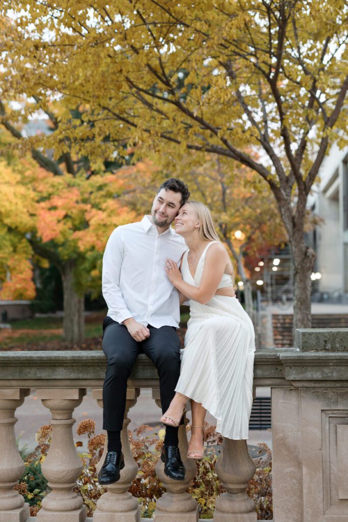 Couple sitting on railing at the Memorial Union engagement session.