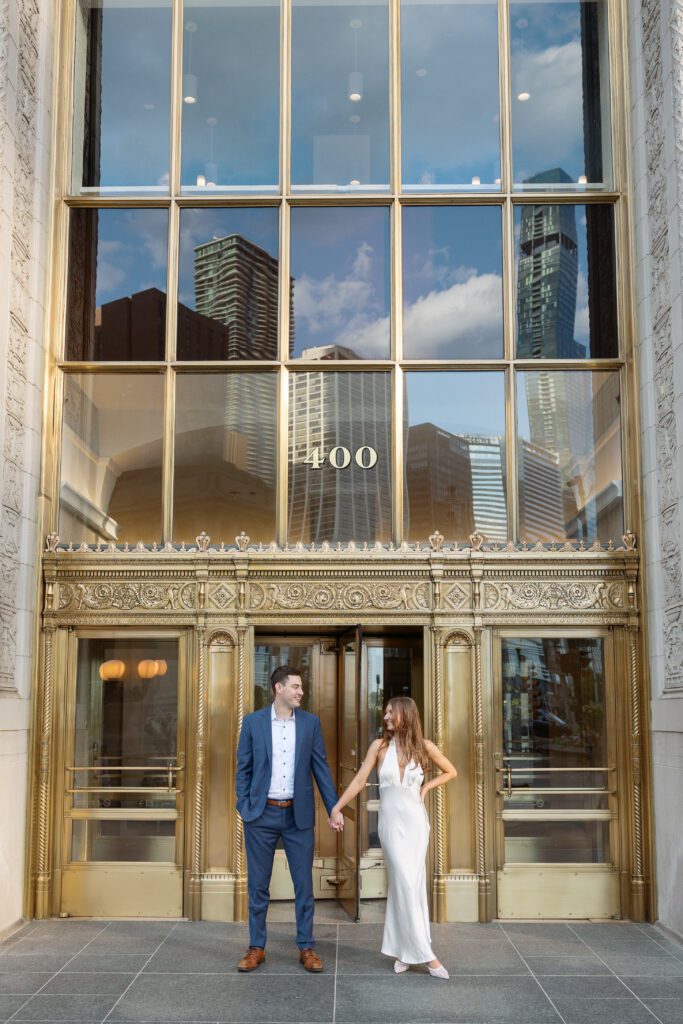 Couple holding hands at their engagement session at the Wrigley Building in Chicago.