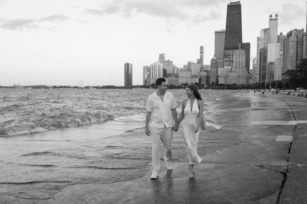 Black and white of couple walking together during their engagement session at North Avenue Beach in Chicago.