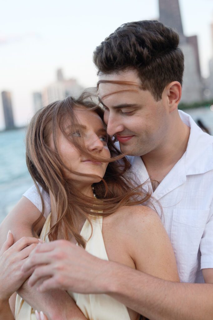 Wind swept portrait of couple hugging at North Avenue Beach engagement session in Chicago.