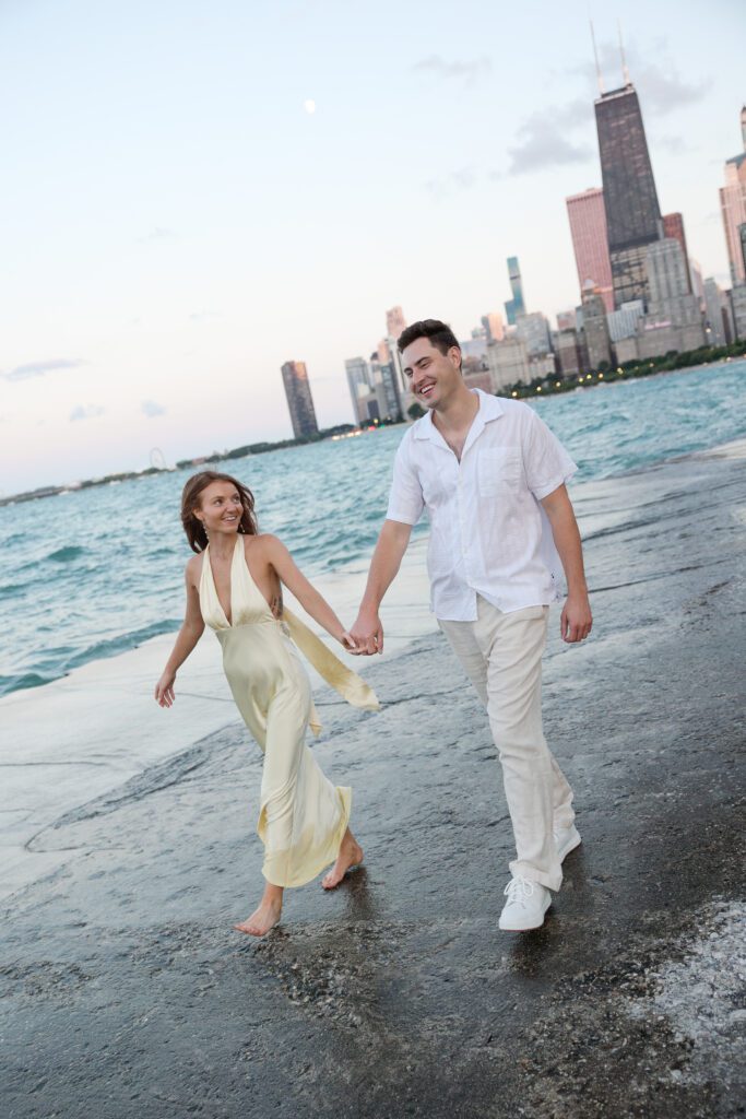 Couple walking hand in hand at their North Avenue Beach Chicago engagement session.