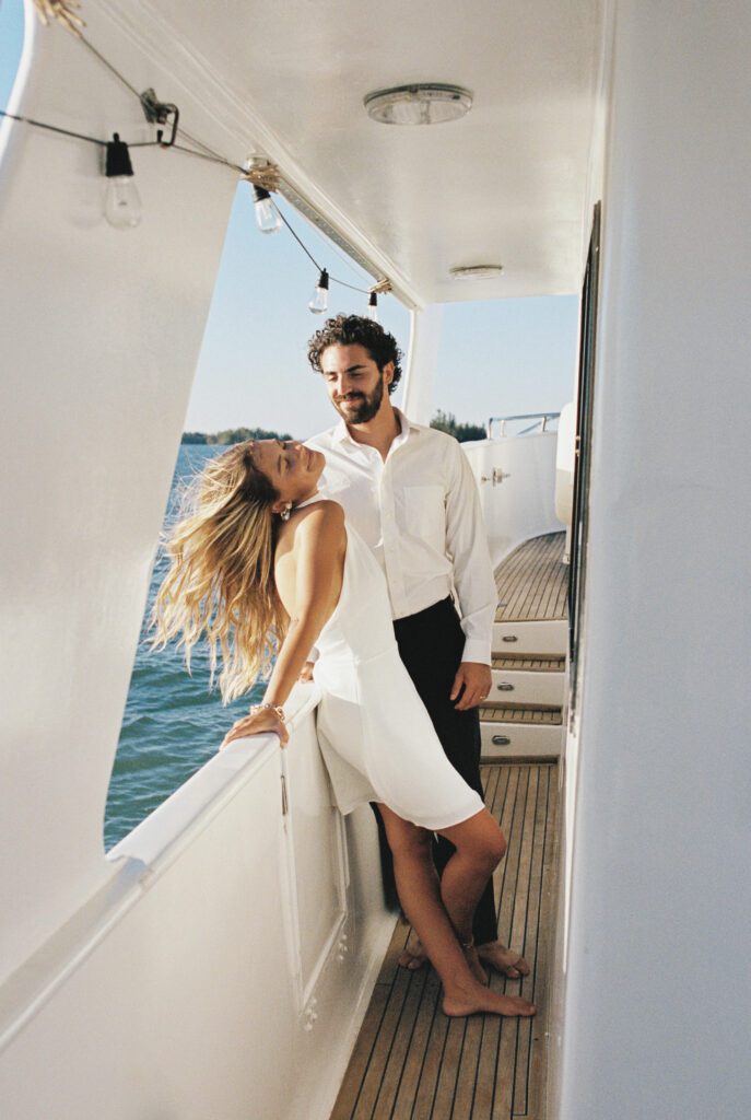 A joyful moment as the bride and groom lean back, allowing the bride's hair to dance in the wind during their elopement on a boat in West Palm Beach, Florida.