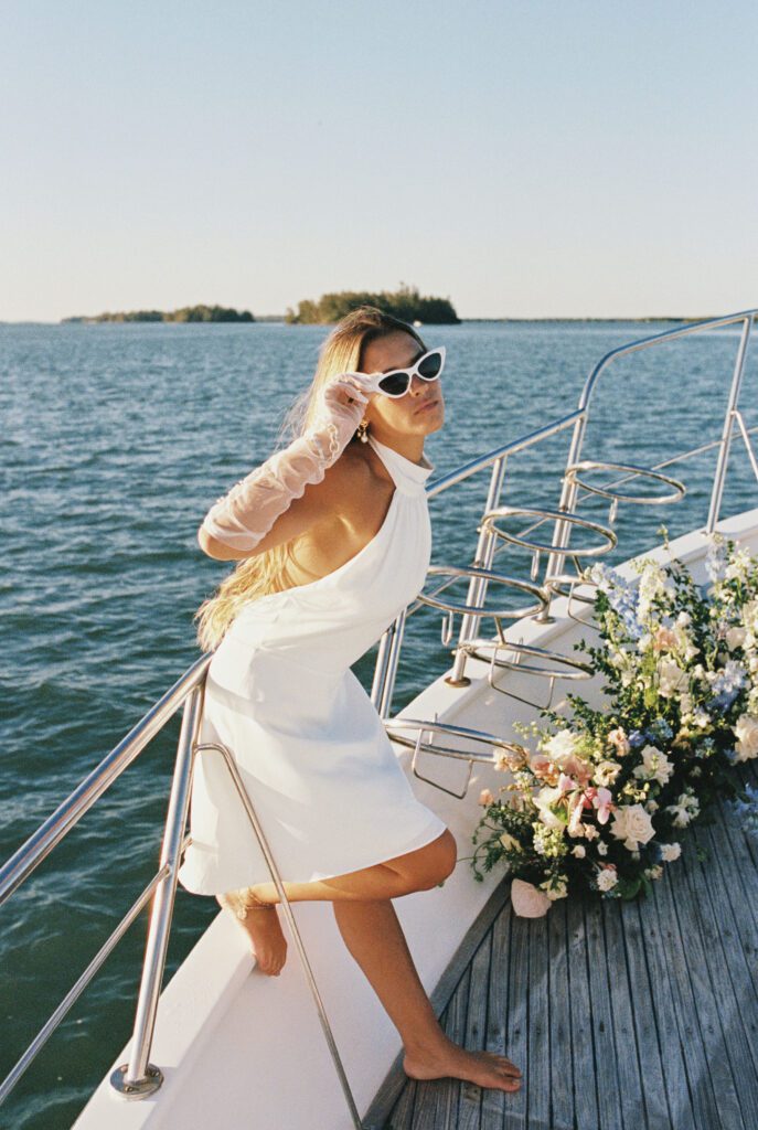 The bride enjoying a sunny day on the yacht, her vintage sunglasses adding a fun twist to her bridal ensemble for the West Palm Beach Boat Elopement.