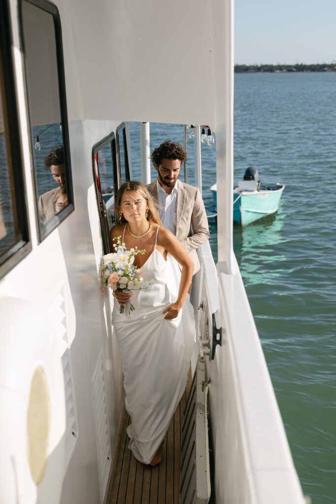 The bride and groom stroll hand-in-hand along the deck of the yacht, stealing loving glances at each other during their West Palm Beach Boat Elopement.