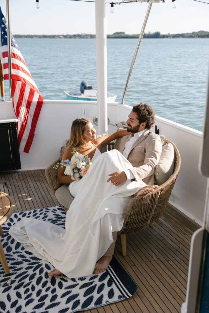 A tender moment of the couple lounging together on a chair, wrapped in each other's arms during their West Palm Beach Boat Elopement.