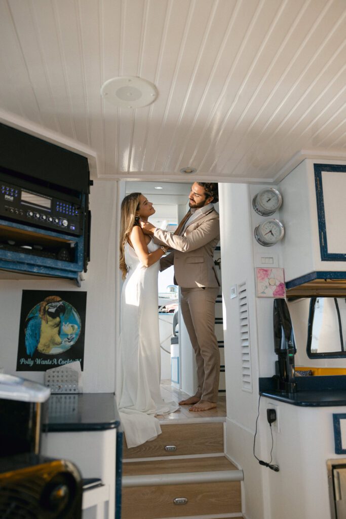 The bride and groom helping each other get ready in the yacht cabin before their West Palm Beach Boat Elopement.