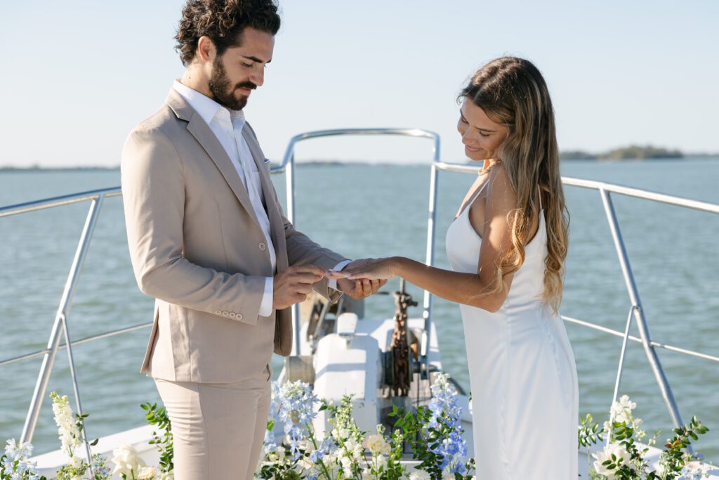 The bride and groom exchanging vows on the deck of the yacht during their West Palm Beach Boat Elopement, with the ocean in the background.