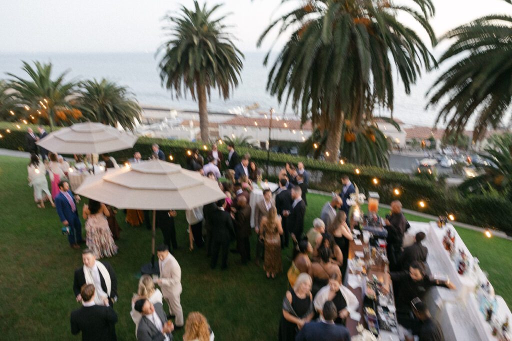 Guests enjoying a stylish outdoor cocktail hour at a Bel Air Bay Club wedding, sipping drinks with a stunning ocean view.