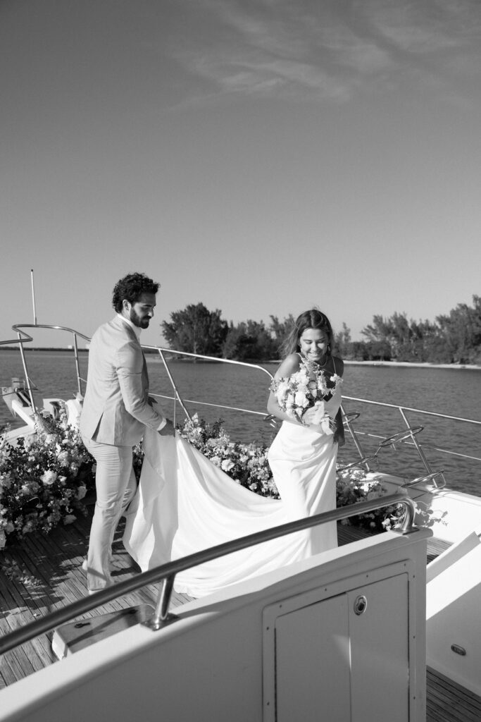 The bride and groom share a joyful moment on the yacht, their laughter illuminated by the golden sunset during their West Palm Beach Boat Elopement.