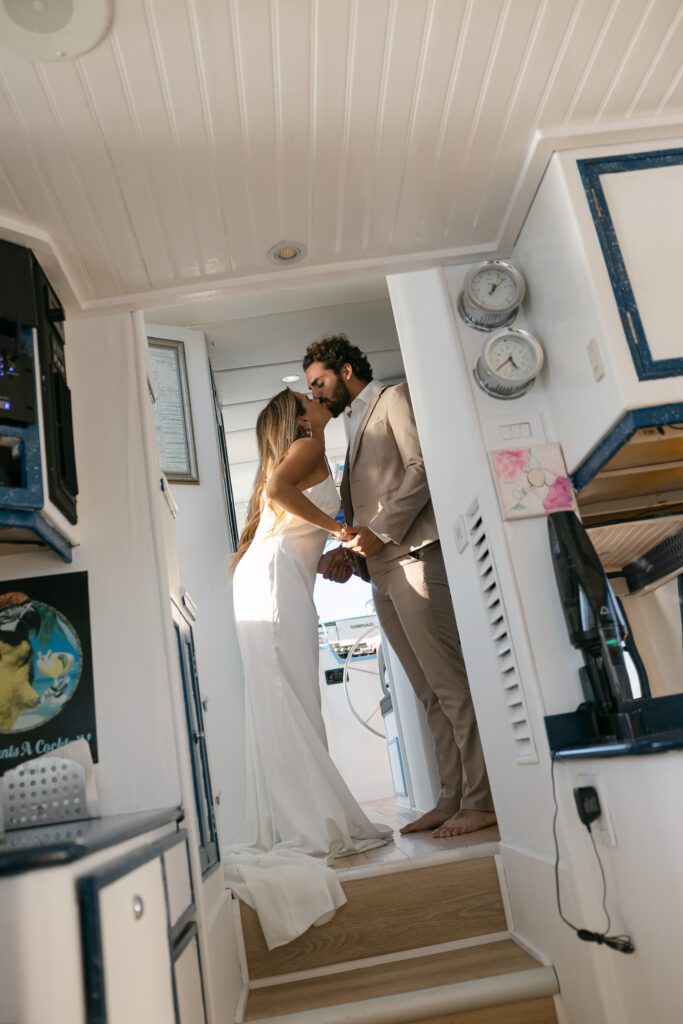 The bride and groom share a sweet kiss as they finish getting ready in the cabin, radiating love and excitement for their West Palm Beach Boat Elopement.