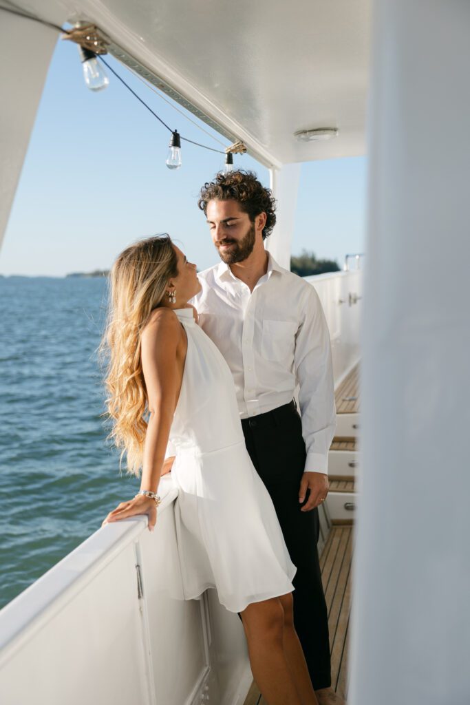 A heartwarming image of the couple cozying up at their elopement on a boat in West Palm Beach, Florida, with the ocean waves gently lapping against the hull.