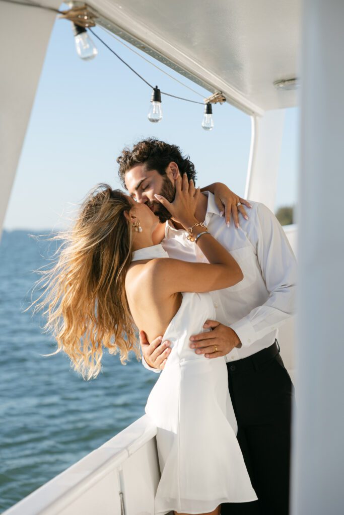 The bride and groom cozily nestled together at their elopement on a boat in West Palm Beach, Florida, enjoying the intimate atmosphere.