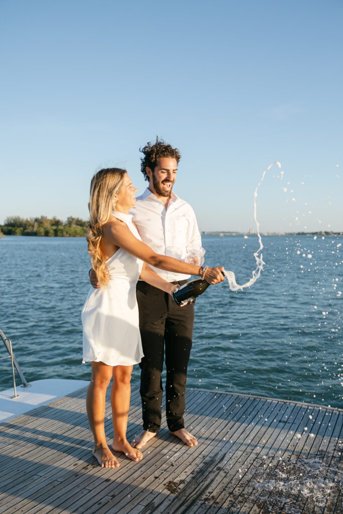 A joyful moment of the couple spraying champagne, creating a fun and festive atmosphere for their West Palm Beach Boat Elopement.